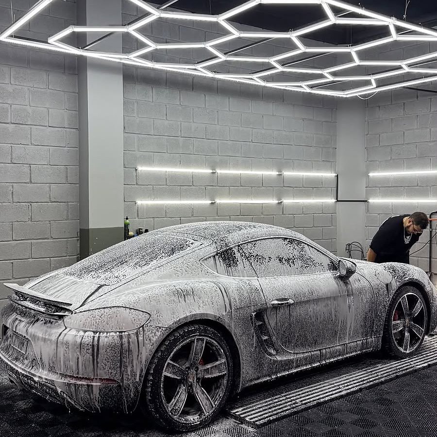 Porsche coberto de espuma durante lavagem profissional, em box com iluminação de LED