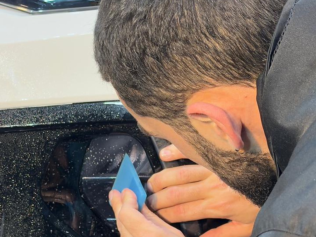 Aplicação detalhada de PPF (película de proteção de pintura) na dianteira de um carro branco